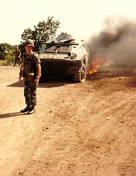 Armored cars, tires flat and burning from combat in Grenada against U.S. forces